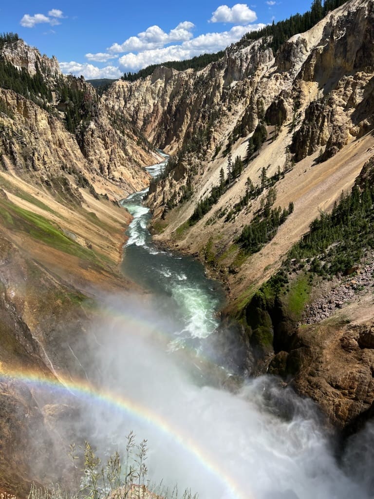 A rainbow is seen in the middle of a canyon.