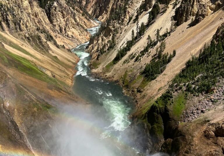 A rainbow is seen in the middle of a canyon.